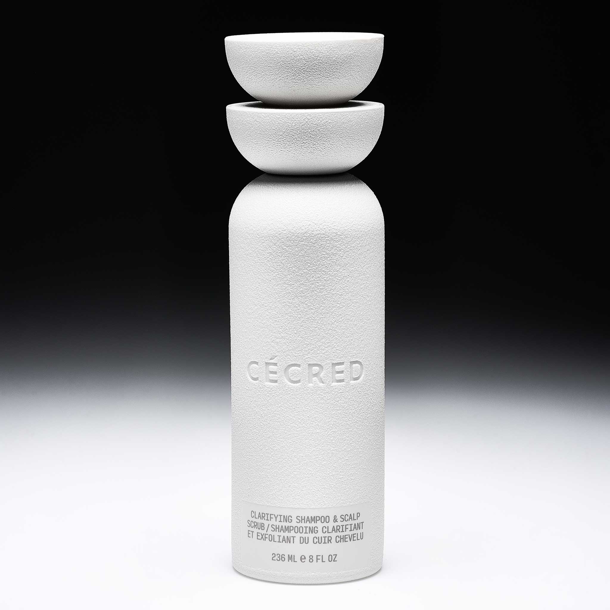 Clarifying Shampoo & Scalp Scrub bottle shown upright, featuring its dual bowl cap silhouette.