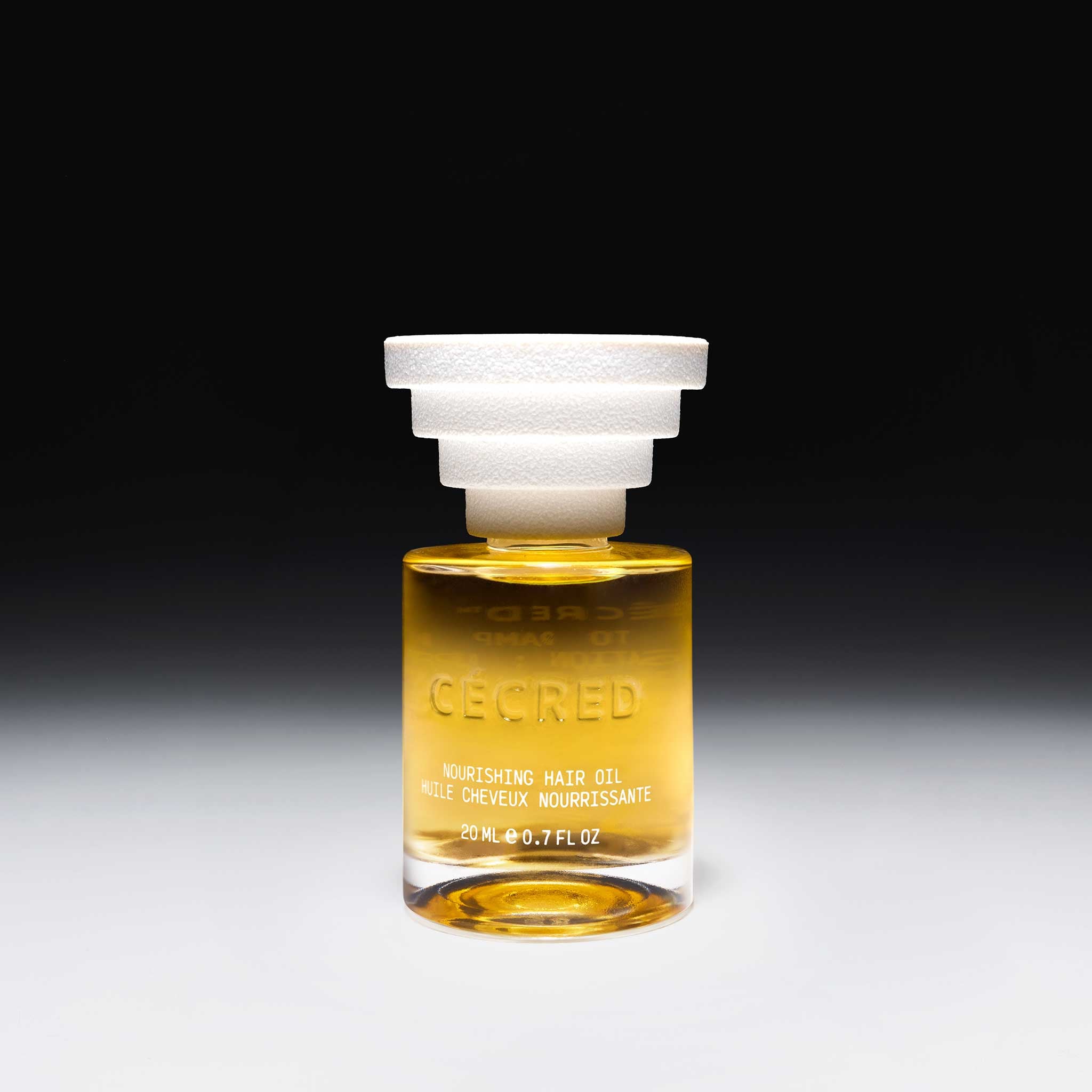Cécred Nourishing Hair Oil bottle displayed upright with signature sculptural cap, against a black gradient backdrop.