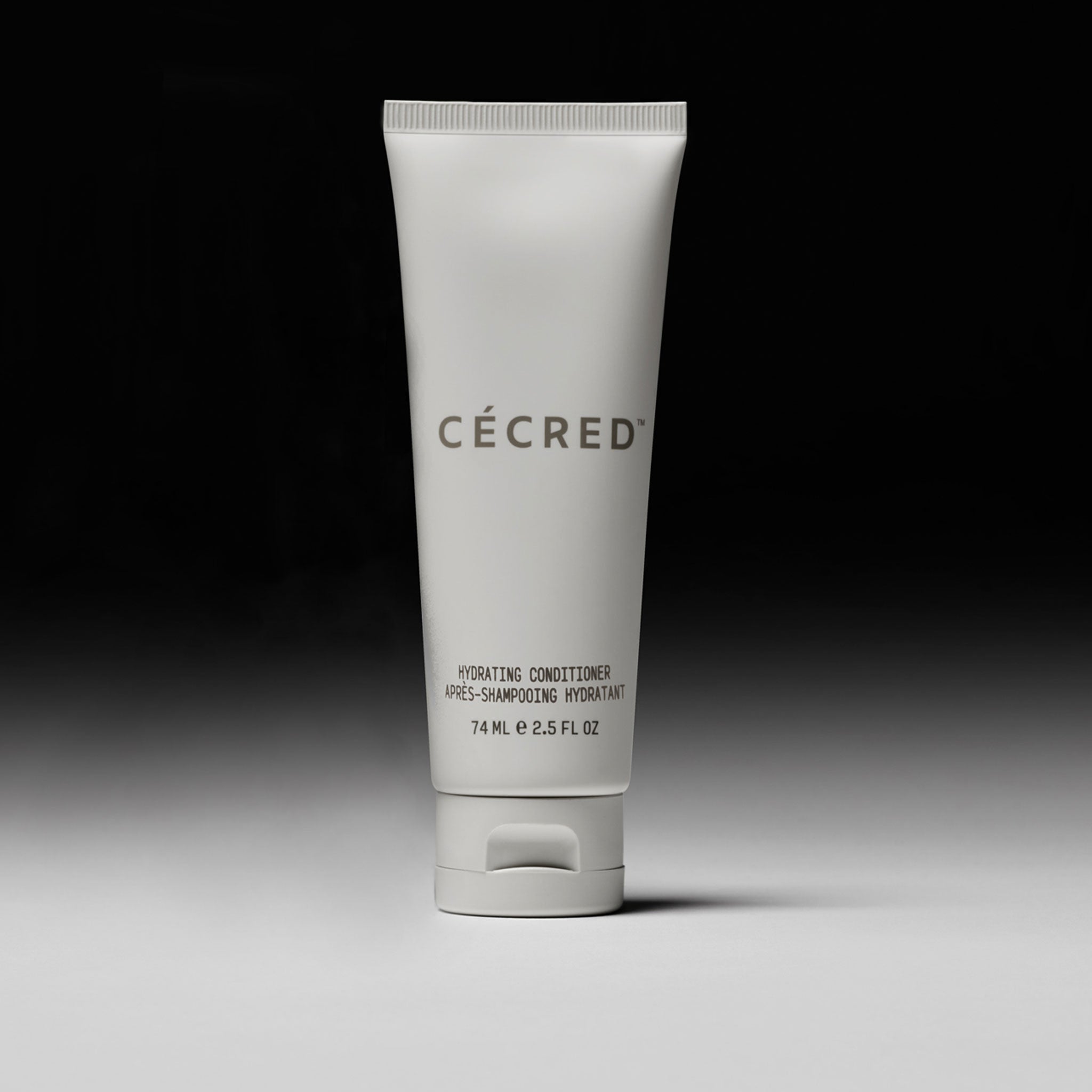 Cécred Hydrating Conditioner in travel size shown against a dark gradient, emphasizing portability and sleek branding.