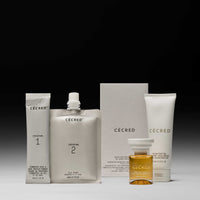Cécred Fortifying Treatment Kit displaying Fermented Rice & Rose Protein Ritual Step 1 and Step 2, Reconstructing Treatment Mask travel size, hair oil, and product box against a gradient grey background